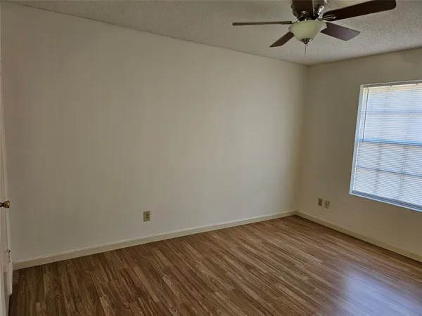 an empty room with a window and ceiling fan