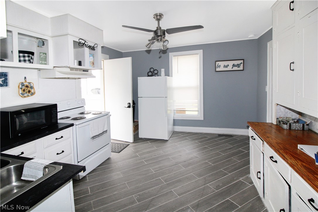 407 Fremont Road Port Clinton, OH 43452 - Photo 4 of 22 Kitchen with white appliances, white cabinetry, ceiling fan, and dark hardwood / wood-style floors