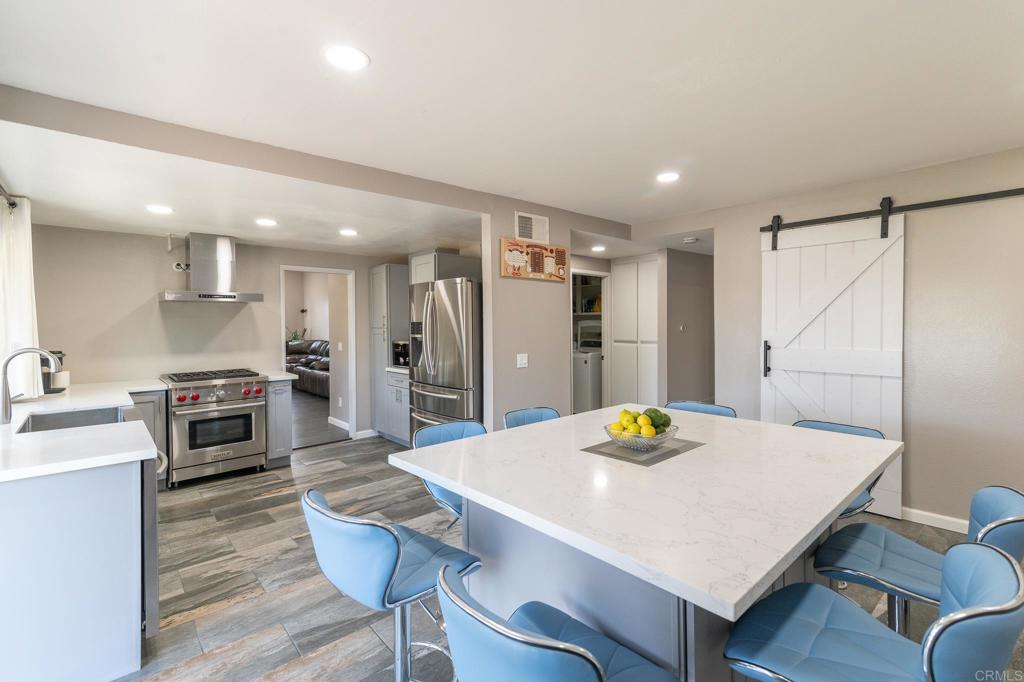 a kitchen with stainless steel appliances a dining table chairs and stove