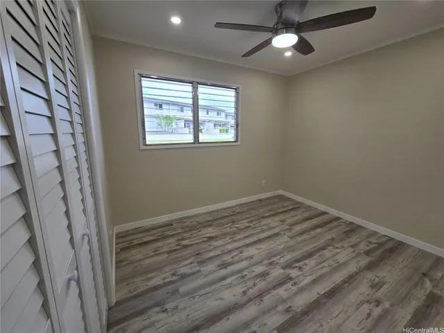 a view of empty room with wooden floor and fan