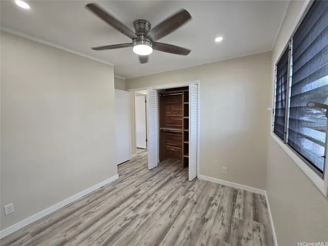 an empty room with closet and a ceiling fan