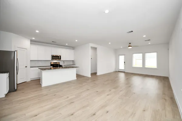 an empty room with wooden floor and natural light