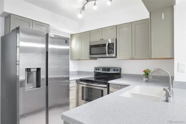 a kitchen with stainless steel appliances a sink a stove a microwave a refrigerator and cabinets