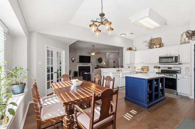 a kitchen with stainless steel appliances granite countertop a stove a sink dishwasher a dining table and chairs with wooden floor