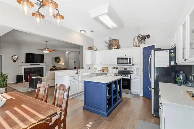 a open kitchen with cabinets a sink dishwasher and a stove with wooden floor