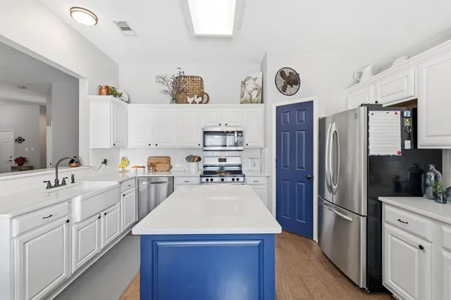 a kitchen with a refrigerator a stove a sink and dishwasher with wooden floor