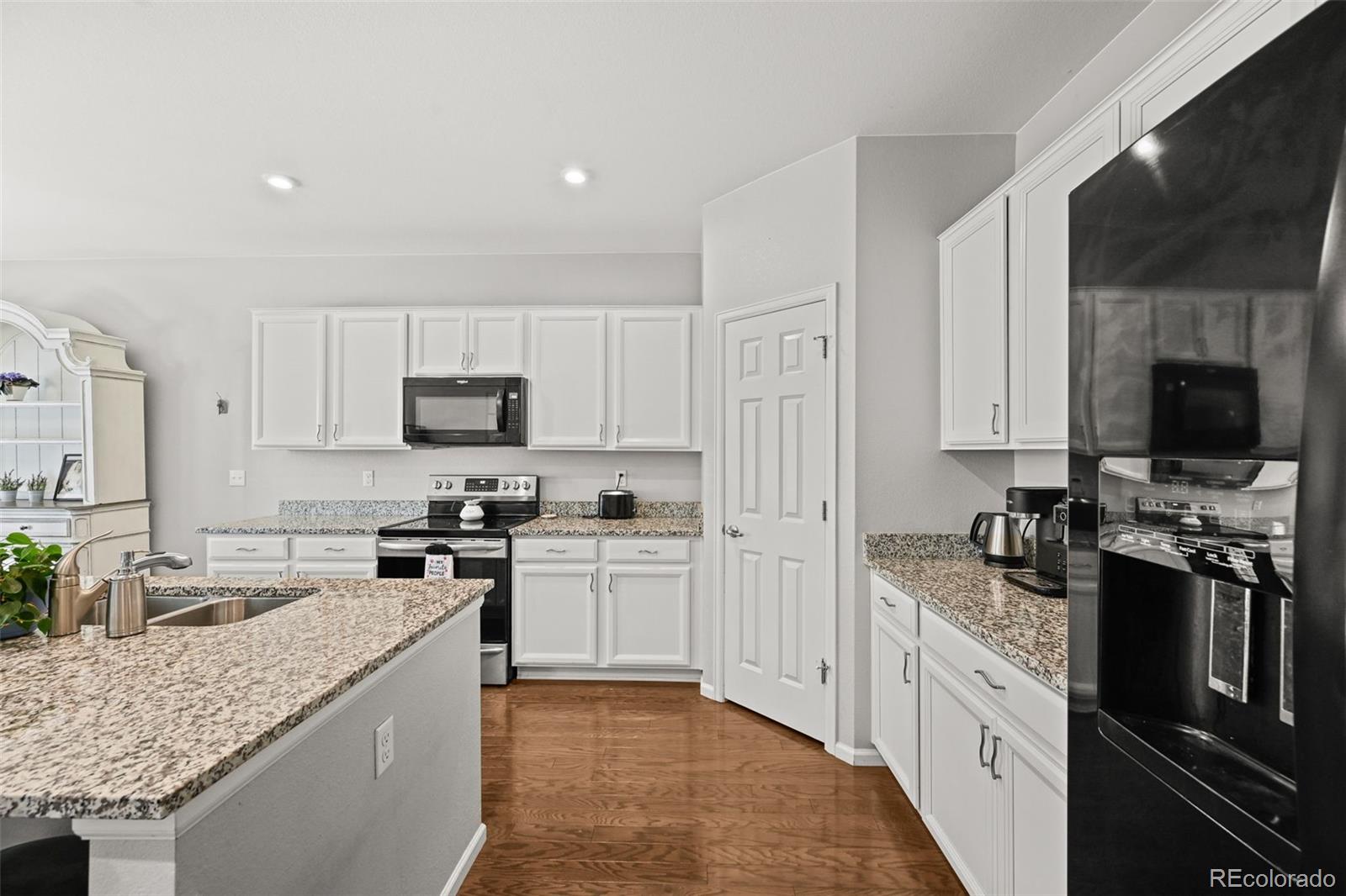 5230 Periwinkle Way Brighton, CO 80640 - Photo 5 of 44 a kitchen with stainless steel appliances granite countertop a stove top oven a sink a refrigerator and white cabinets