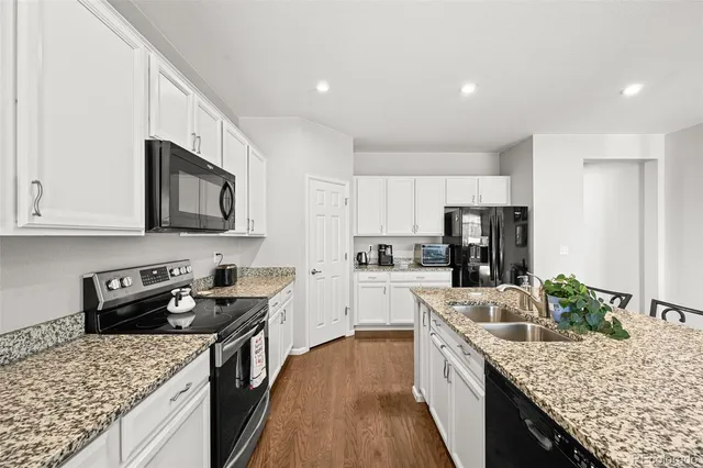 a kitchen with stainless steel appliances granite countertop a stove top oven a sink dishwasher a refrigerator and a oven with wooden floor