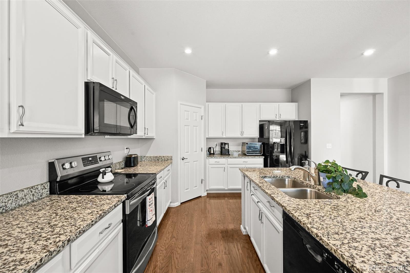 5230 Periwinkle Way Brighton, CO 80640 - Photo 7 of 44 a kitchen with stainless steel appliances granite countertop a stove top oven a sink dishwasher a refrigerator and a oven with wooden floor