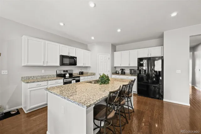 a kitchen with a table and refrigerator a microwave a sink and cabinets