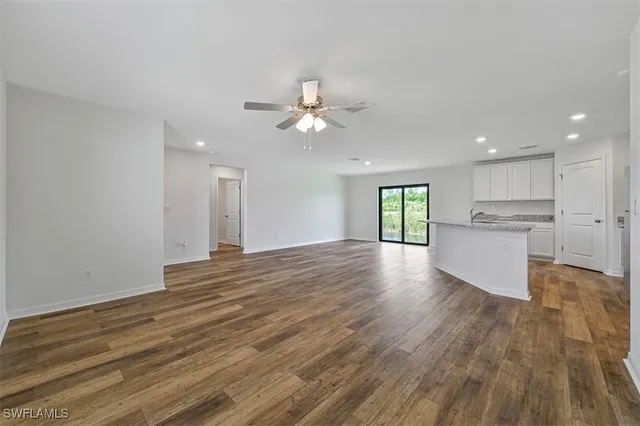 a view of an empty room with kitchen and kitchen view