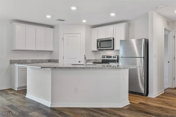 a kitchen with stainless steel appliances granite countertop a refrigerator a sink a stove a microwave and white cabinets