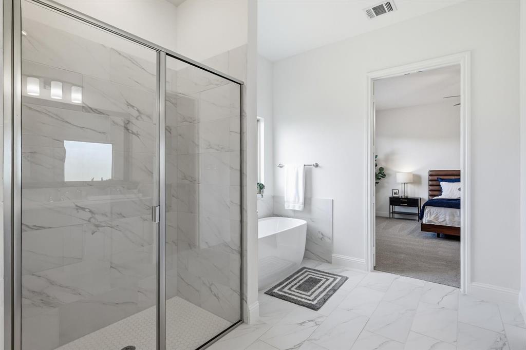 4017 Eagles Bluff Road Midlothian, TX 76065 - Photo 30 of 38 Spacious bathroom featuring a glass-enclosed shower with white hexagon tile flooring, a freestanding soaking tub, and large format marble-look tile flooring