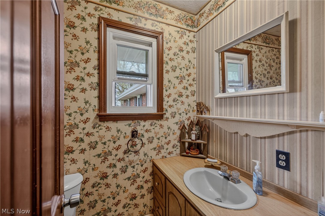8675 West Smith Road Medina, OH 44256 - Photo 14 of 25 Bathroom vanity with a wood-finish countertop, undermount sink, and wall-mounted mirror