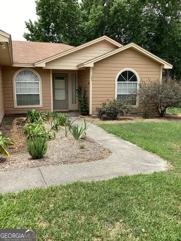 a view of a white house next to a yard and large trees