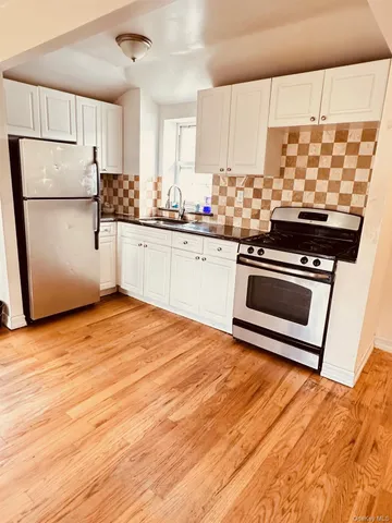 a kitchen with stainless steel appliances a stove a sink and white cabinets