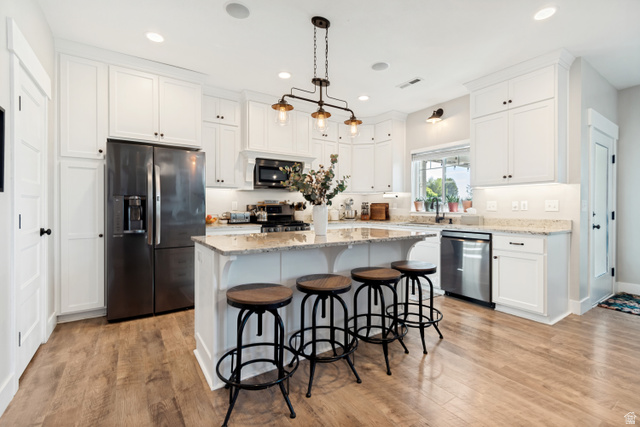 332 South 500 West Payson, UT 84651 - Photo 11 of 50 Open-concept kitchen featuring white cabinetry, granite countertops, wood style lvp flooring, a central island with seating, and stainless steel appliances
