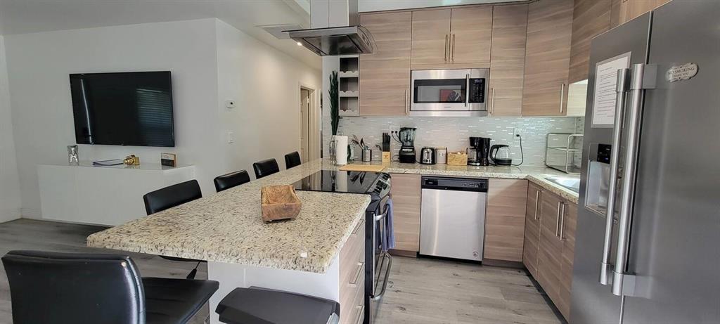4154 Southwest 49th Street Dania Beach, FL 33314 - Photo 25 of 30 a kitchen with a table chairs refrigerator and microwave