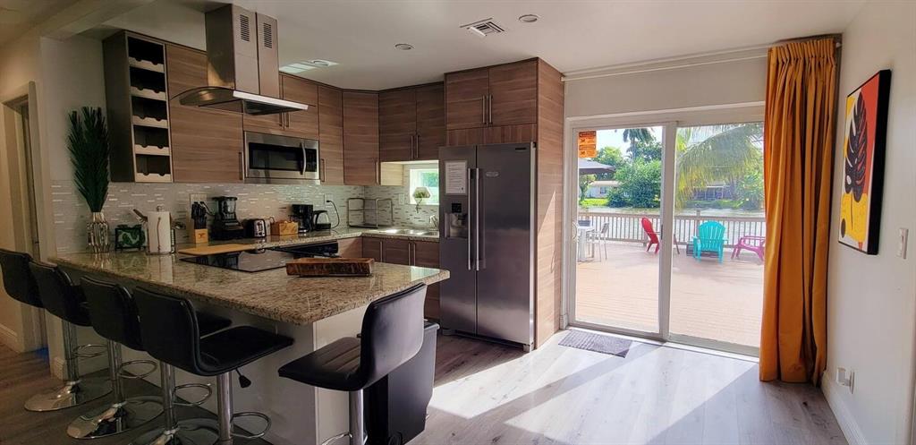 4154 Southwest 49th Street Dania Beach, FL 33314 - Photo 3 of 30 a kitchen with stainless steel appliances granite countertop a refrigerator a sink dishwasher a stove a dining table and chairs with wooden floor