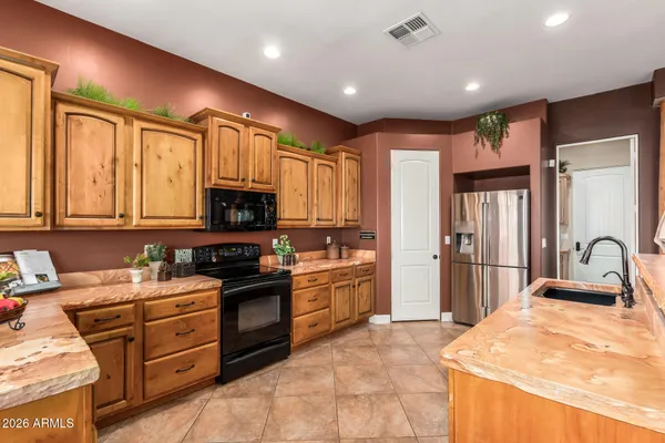 a kitchen with a stove a sink a counter top space and living room view