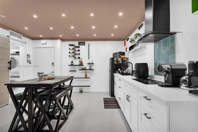 a kitchen with stainless steel appliances kitchen island granite countertop a table chairs sink and white cabinets