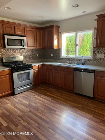 a kitchen with stainless steel appliances granite countertop a stove a sink and a microwave