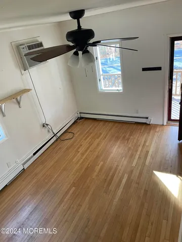 an empty room with wooden floor fan and windows