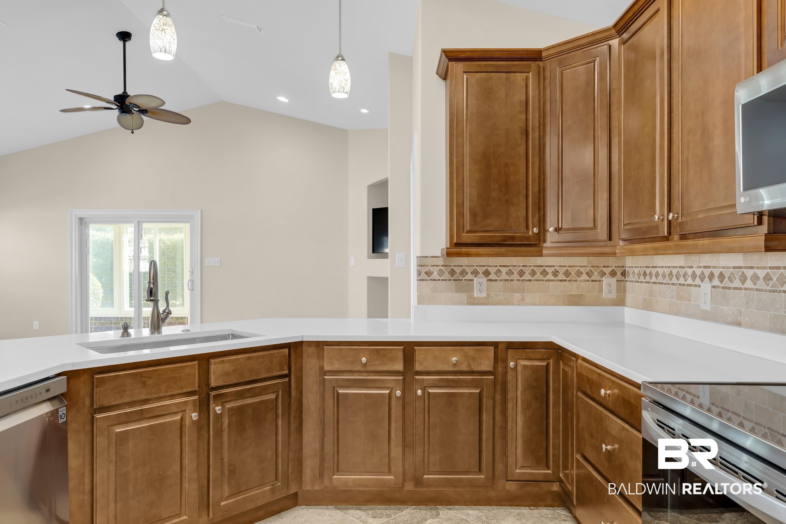 226 Hemingway Loop Foley, AL 36535 - Photo 7 of 53 Kitchen featuring lofted ceiling, brown cabinets, stainless steel appliances, tasteful backsplash, and hanging light fixtures