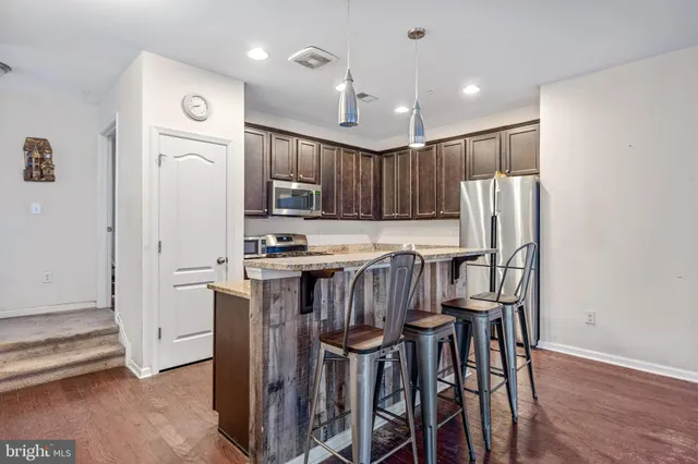 a kitchen with kitchen island wooden cabinets and refrigerator