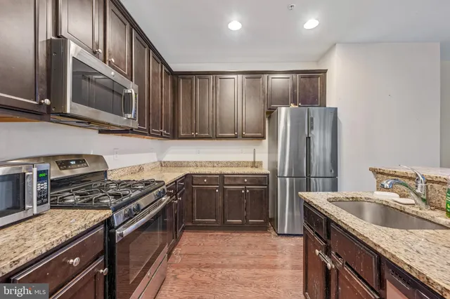 a kitchen with granite countertop a sink stove and refrigerator