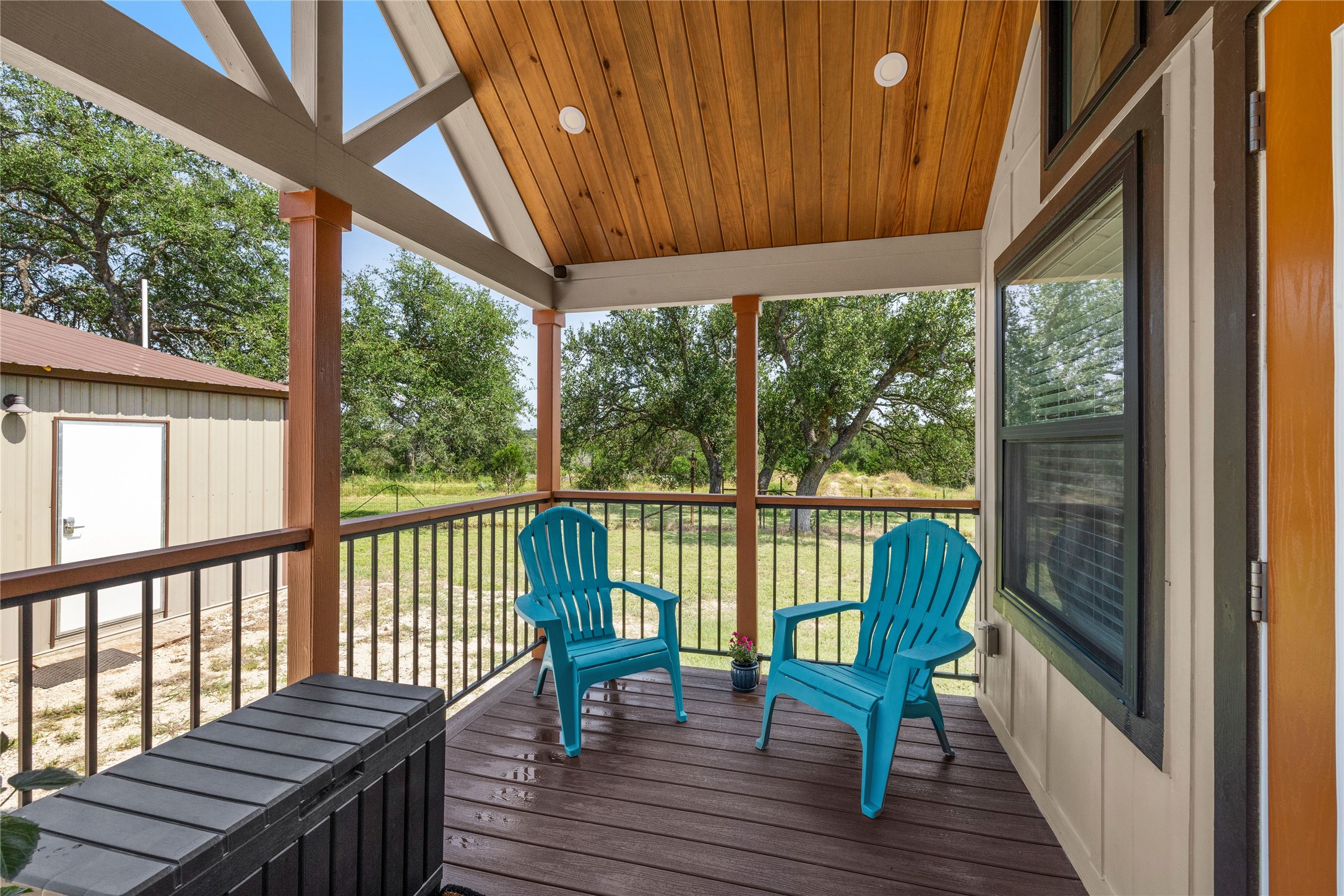8200 Ranch Road 12 San Marcos, TX 78666 - Photo 11 of 40 A welcoming covered porch with a rich wooden ceiling offers a peaceful view of the green landscape.
