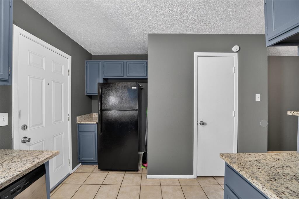 10500 Lake June Road, Unit L07 Dallas, TX 75217 - Photo 8 of 14 Spacious kitchen featuring granite-style countertops, stainless steel appliances, blue cabinetry with traditional paneling, tile flooring, and ample counter workspace