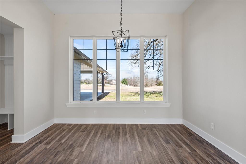 4003 Nettle Road Streetman, TX 75859 - Photo 11 of 33 an empty room with wooden floor chandelier and windows