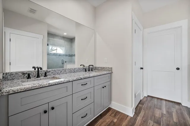 a bathroom with a granite countertop double vanity sink and mirror