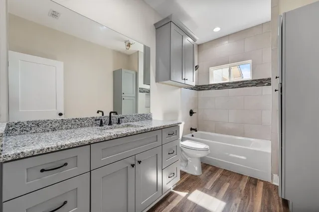 a bathroom with a granite countertop toilet a sink and a mirror