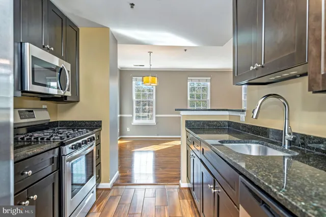 a kitchen with granite countertop a sink a stove cabinets and stainless steel appliances