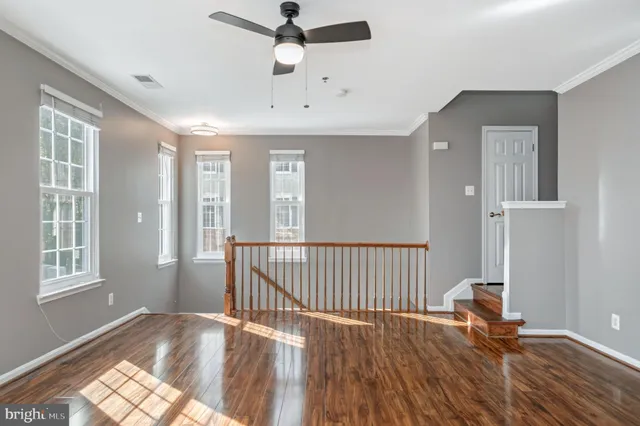 a view of a livingroom with wooden floor and a ceiling fan
