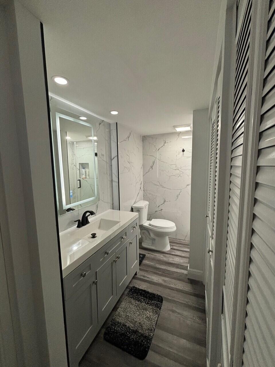 250 Northeast 20th Street, Unit 124S Boca Raton, FL 33431 - Photo 11 of 14 a bathroom with a double vanity sink a toilet and a mirror