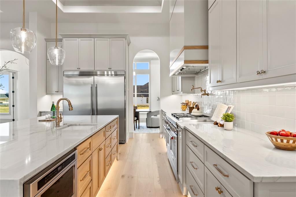 724 Cooper Trail Weatherford, TX 76087 - Photo 16 of 40 Kitchen with light stone countertops, pendant lighting, light wood-type flooring, and a kitchen island with sink