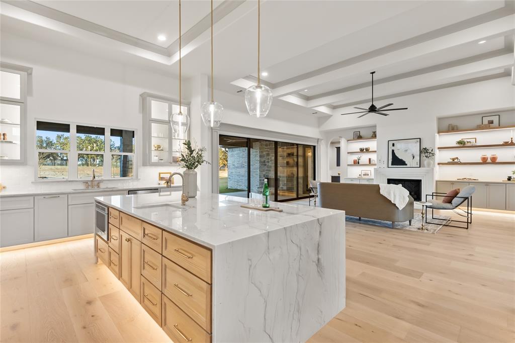 724 Cooper Trail Weatherford, TX 76087 - Photo 40 of 40 Kitchen with a fireplace, light wood-style flooring, hanging light fixtures, open floor plan, and beamed ceiling