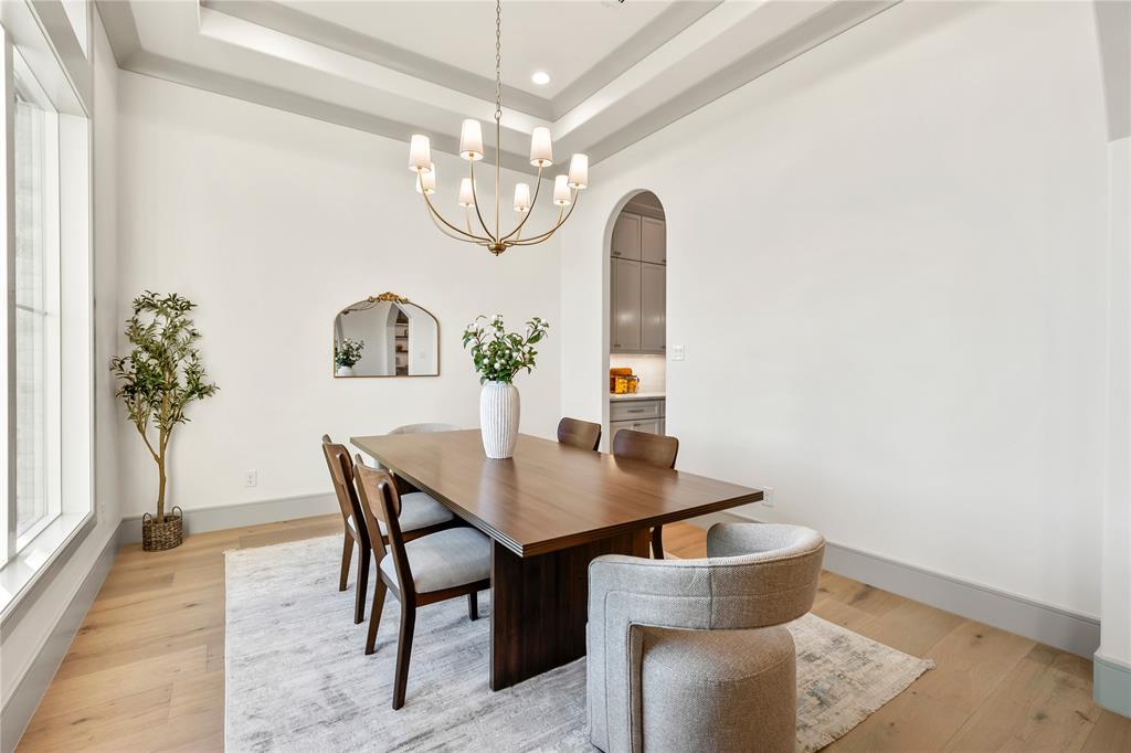 724 Cooper Trail Weatherford, TX 76087 - Photo 8 of 40 Dining area featuring a tray ceiling, light wood finished floors, arched walkways, and a chandelier