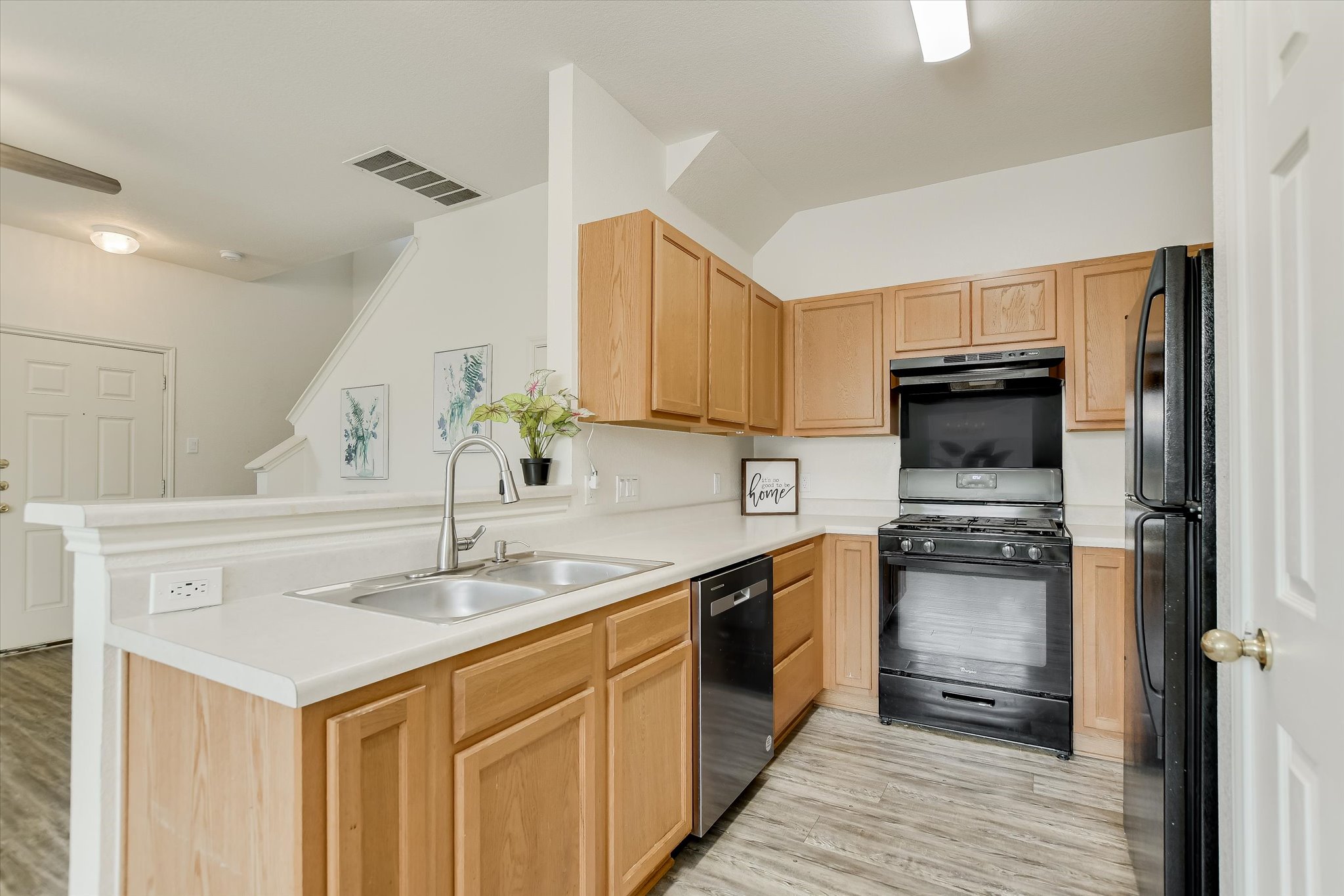 809 Sebastian Bend, Unit B Pflugerville, TX 78660 - Photo 10 of 34 Kitchen with black appliances, light countertops, light wood finish cabinets, and a peninsula