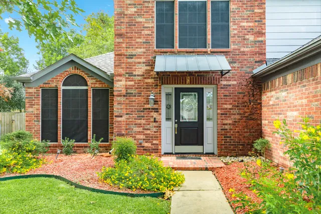 a view of a brick house with brick walls plants and large tree