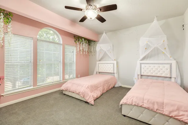 a bedroom with two large bed and a chandelier fan