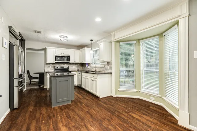 a kitchen with granite countertop a stove a sink and a microwave