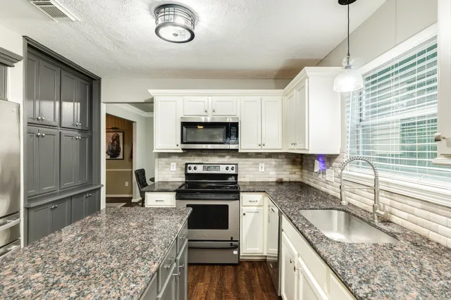 a kitchen with granite countertop a refrigerator stove and sink