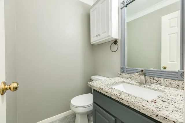 a bathroom with a granite countertop sink and a toilet