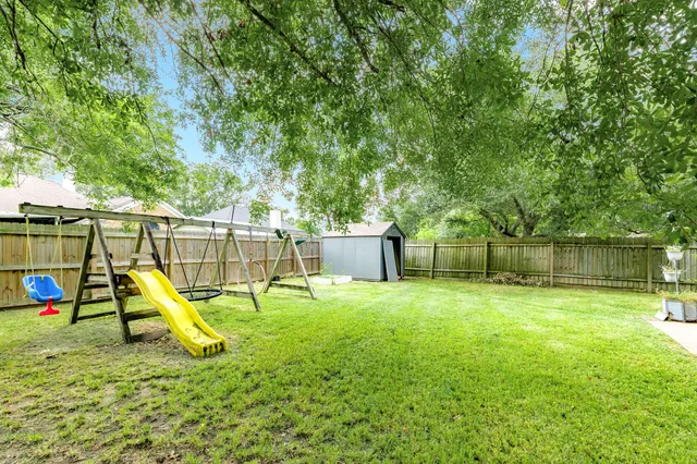 a view of a backyard with a slide and a tree