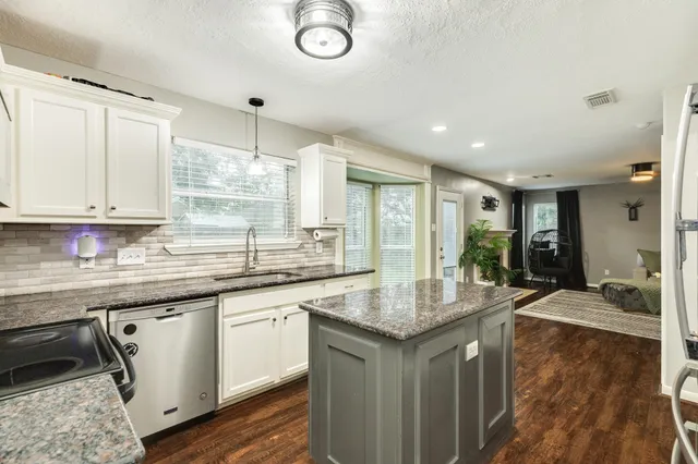 a kitchen with granite countertop a sink stove and cabinets