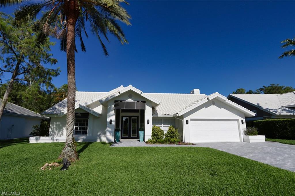 Ranch-style house featuring french doors, a garage, a front yard, decorative driveway, and a chimney